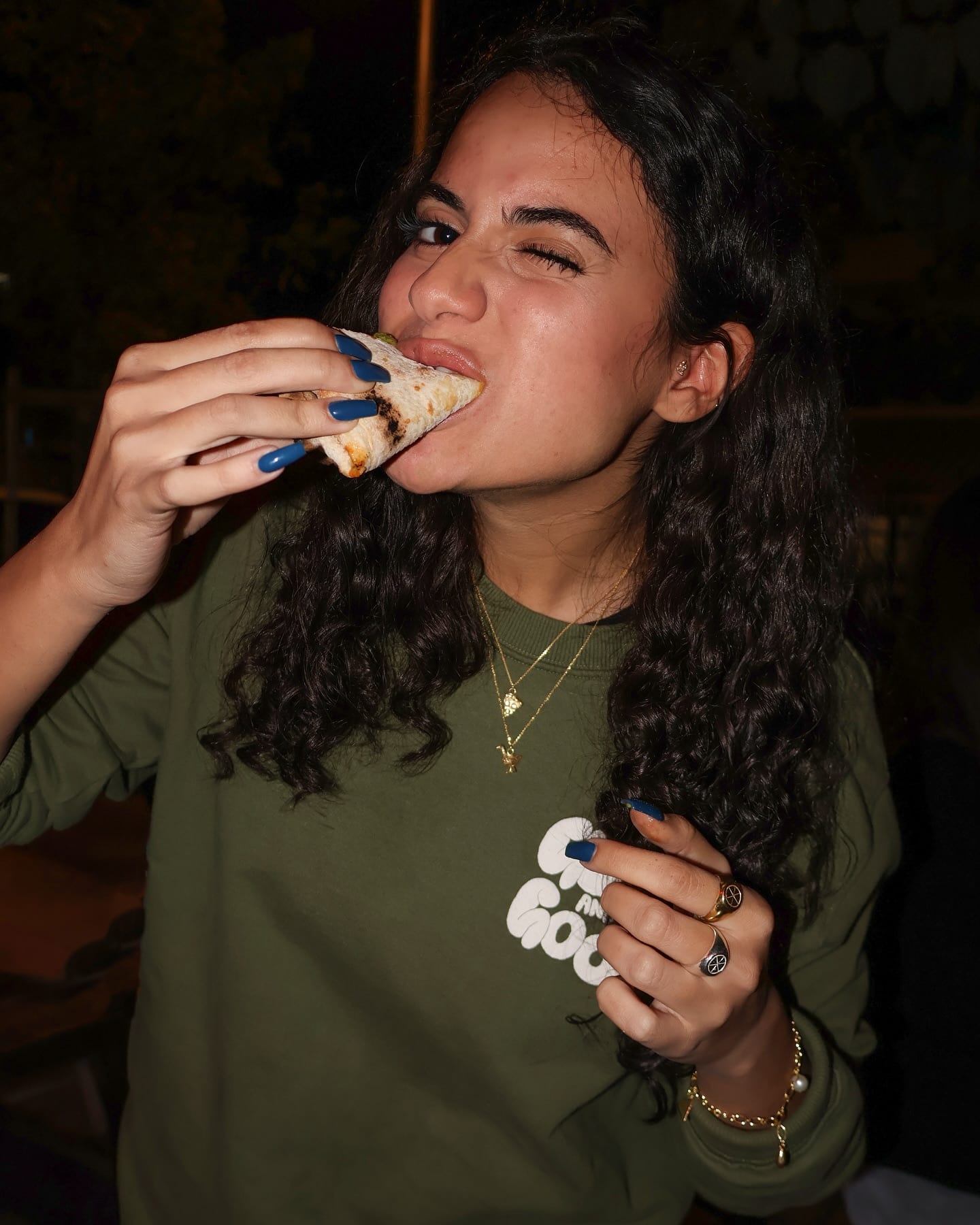 Biting into a folded slice of pizza in a Guido & The Goose t-shirt